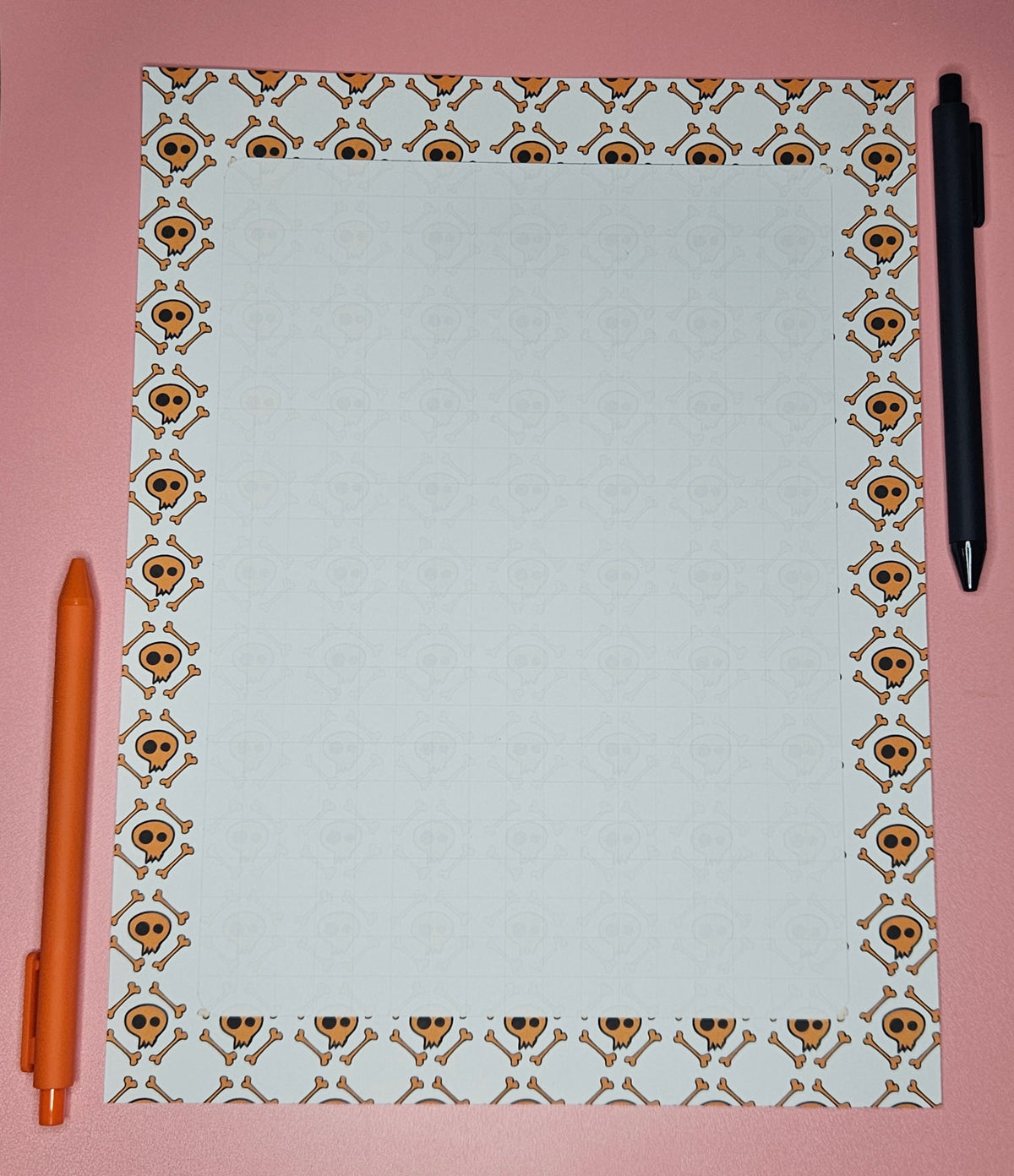 page of paper with a faint grid, orange skulls and bones all over