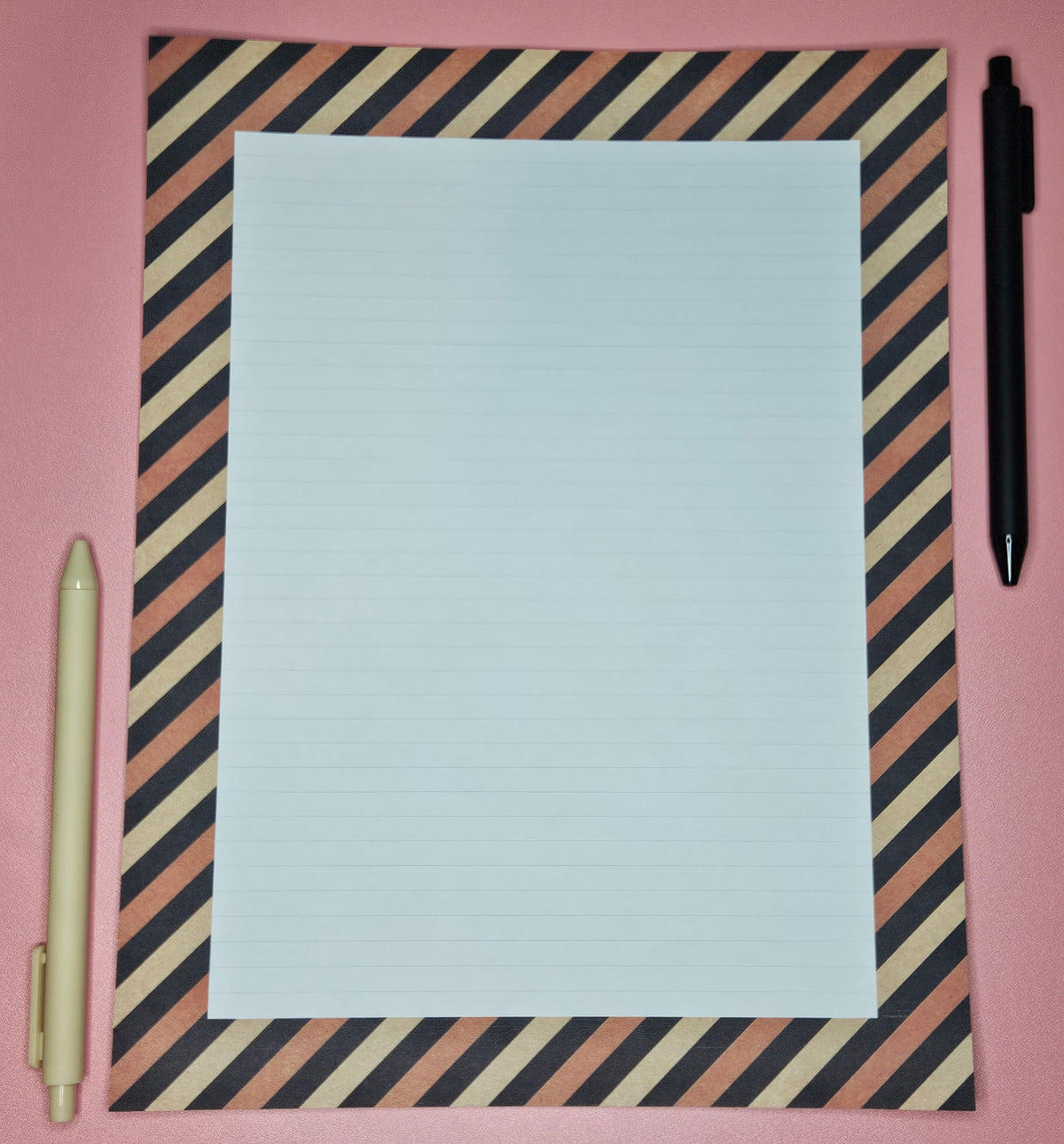 page on a light pink background with black and orange stripes with light college ruled lines